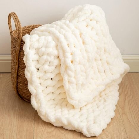 Cream-colored chunky hand-woven blanket draped over a basket